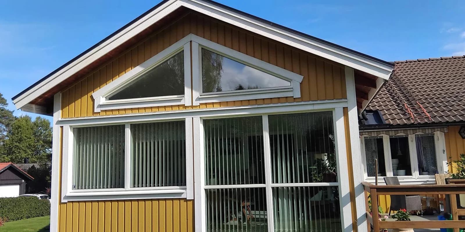 Samma gavel med gul stående panel och vita lister efter fasadtvätt